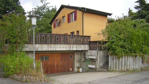 Kleines Haus mit grosser Werkstatt/Garage und grünem Garten.
